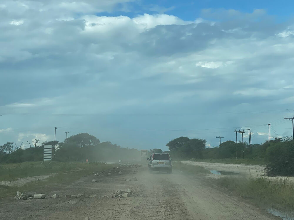 Car driving on dirt road with potholes and rocks