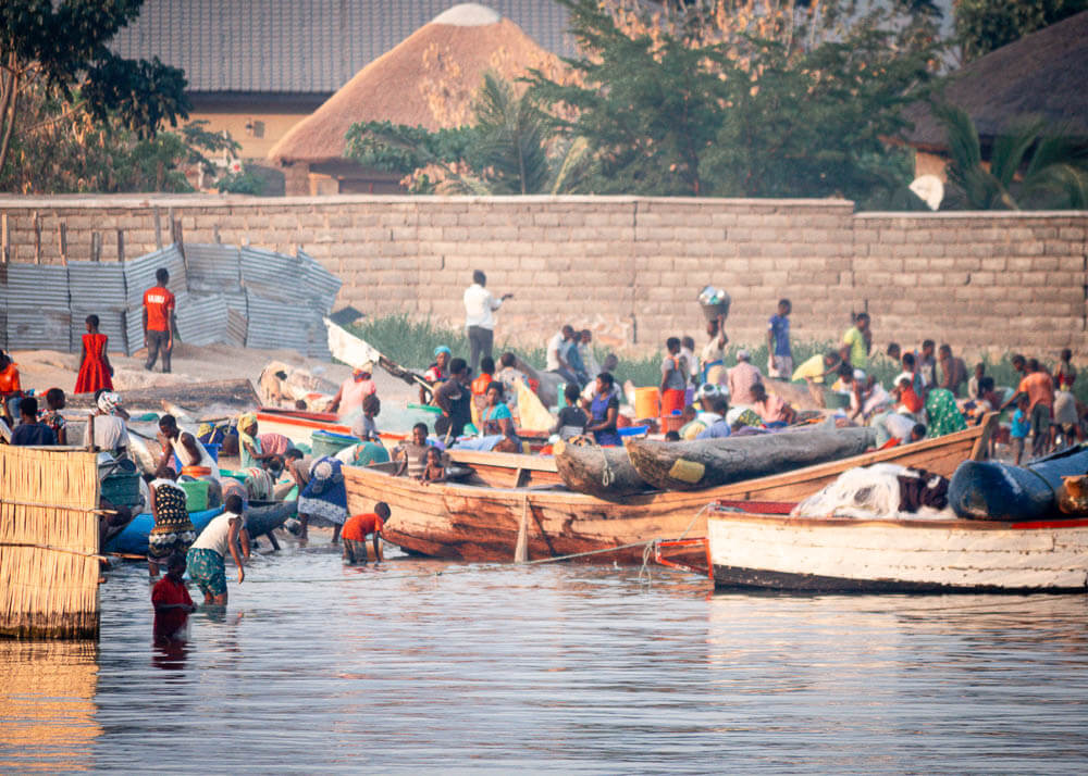 People in amongst boats at waters edge of Lake Malawi