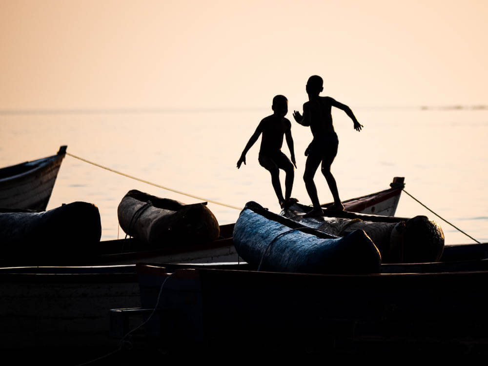 Silhouette of two kids playing off the fishing boats in Lake Malawi