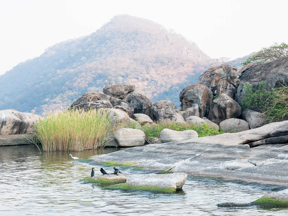 View of hills with water and rocks in foreground