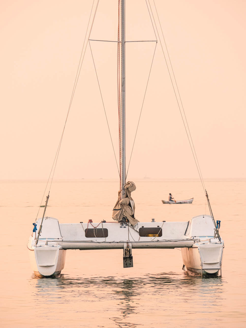 Sail boat anchored in sunset pink waters