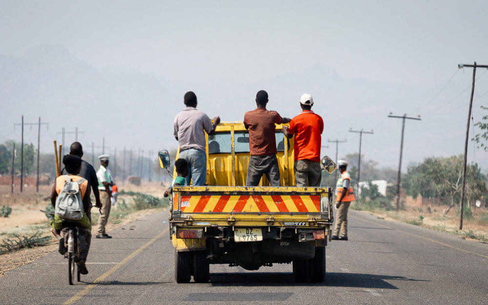 A yellow truck driving on the road towards a police roadblock